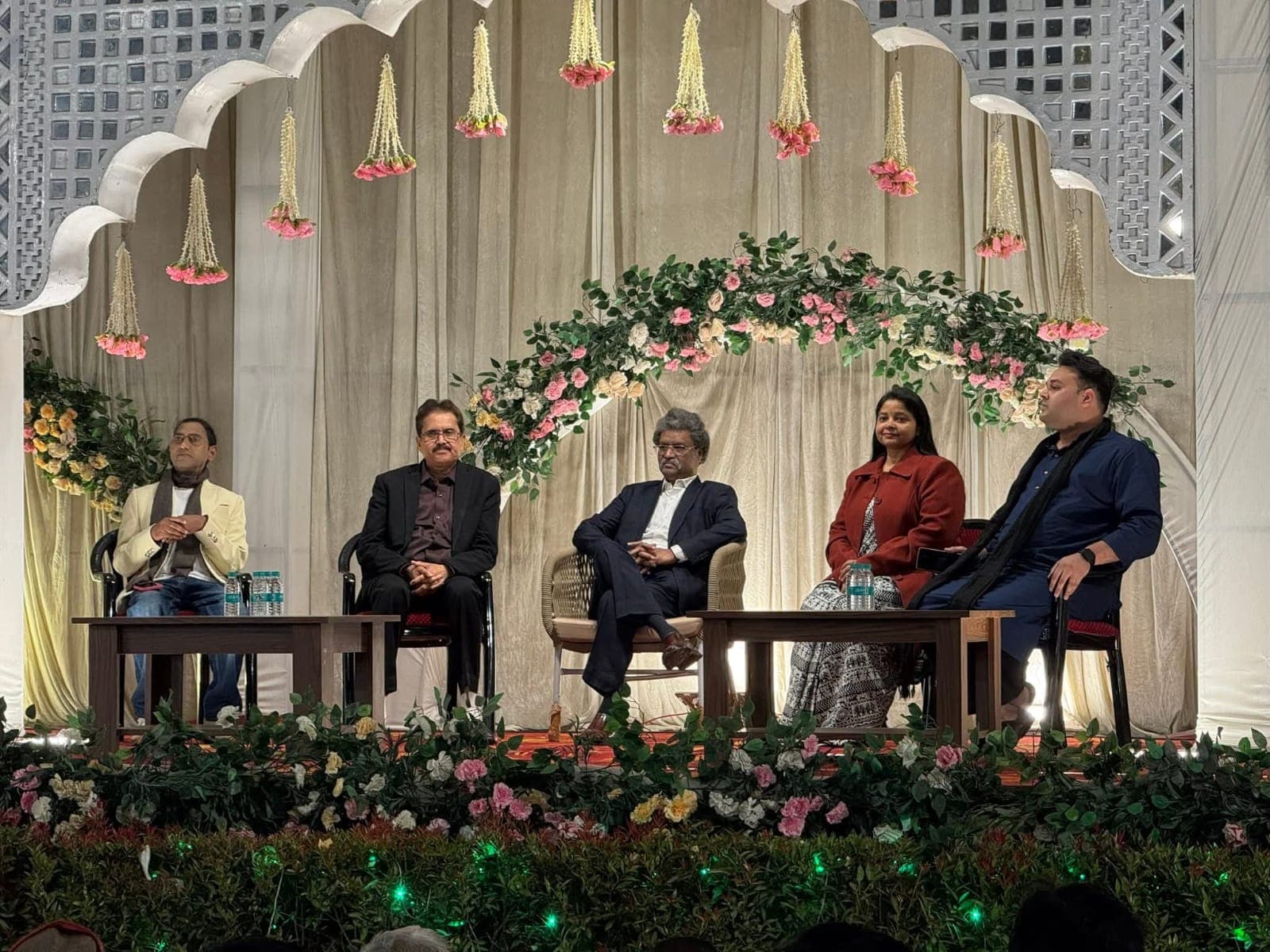 Speakers seated on a decorated stage during a poetry event
