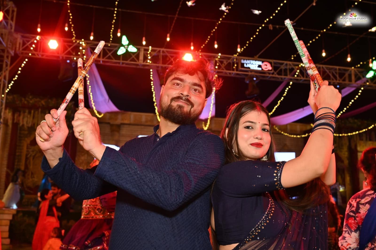 Guests holding dandiya sticks during a festive evening at Adarsh Vatika