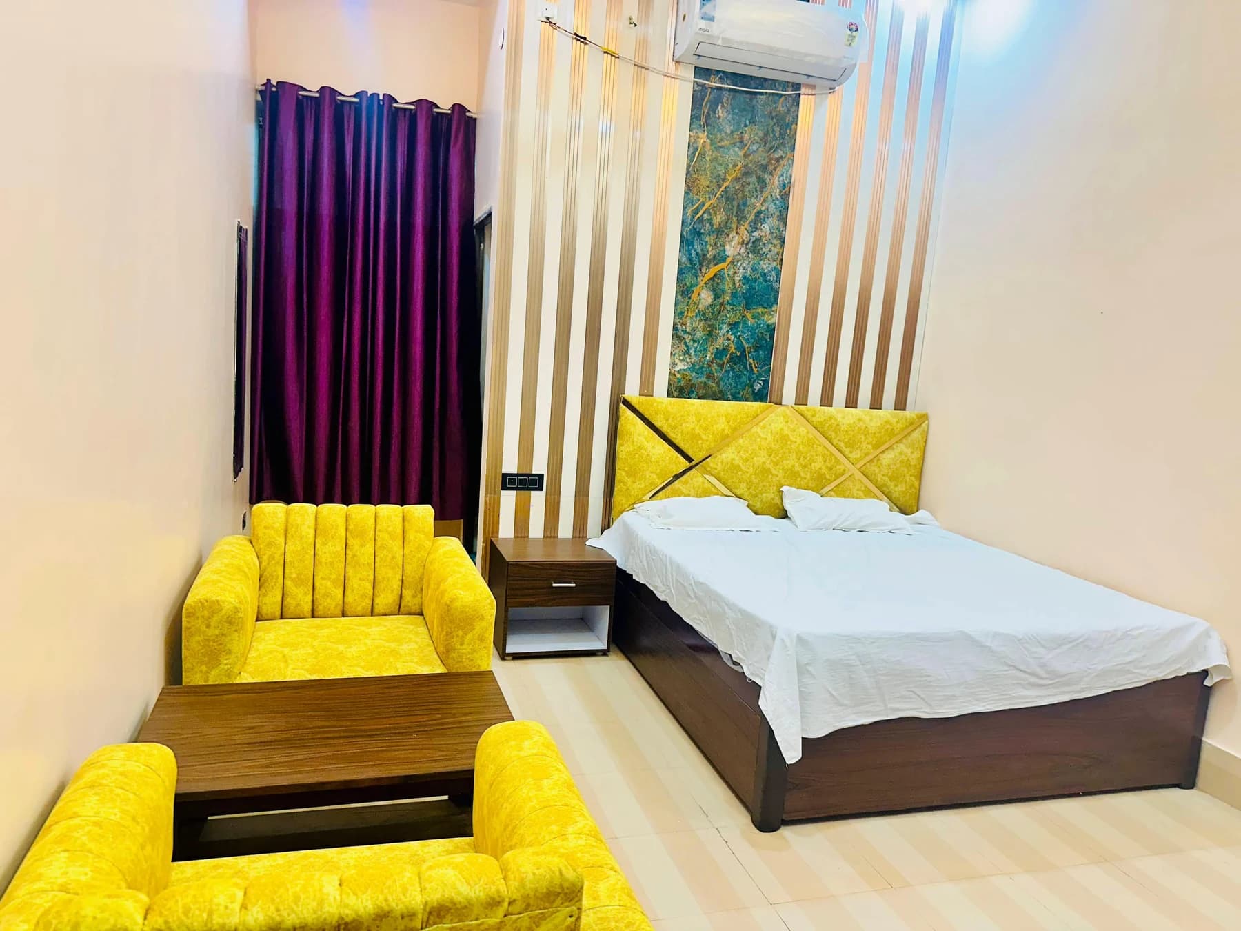 Adarsh Vatika air-conditioned guest room with a double bed and yellow lounge seating